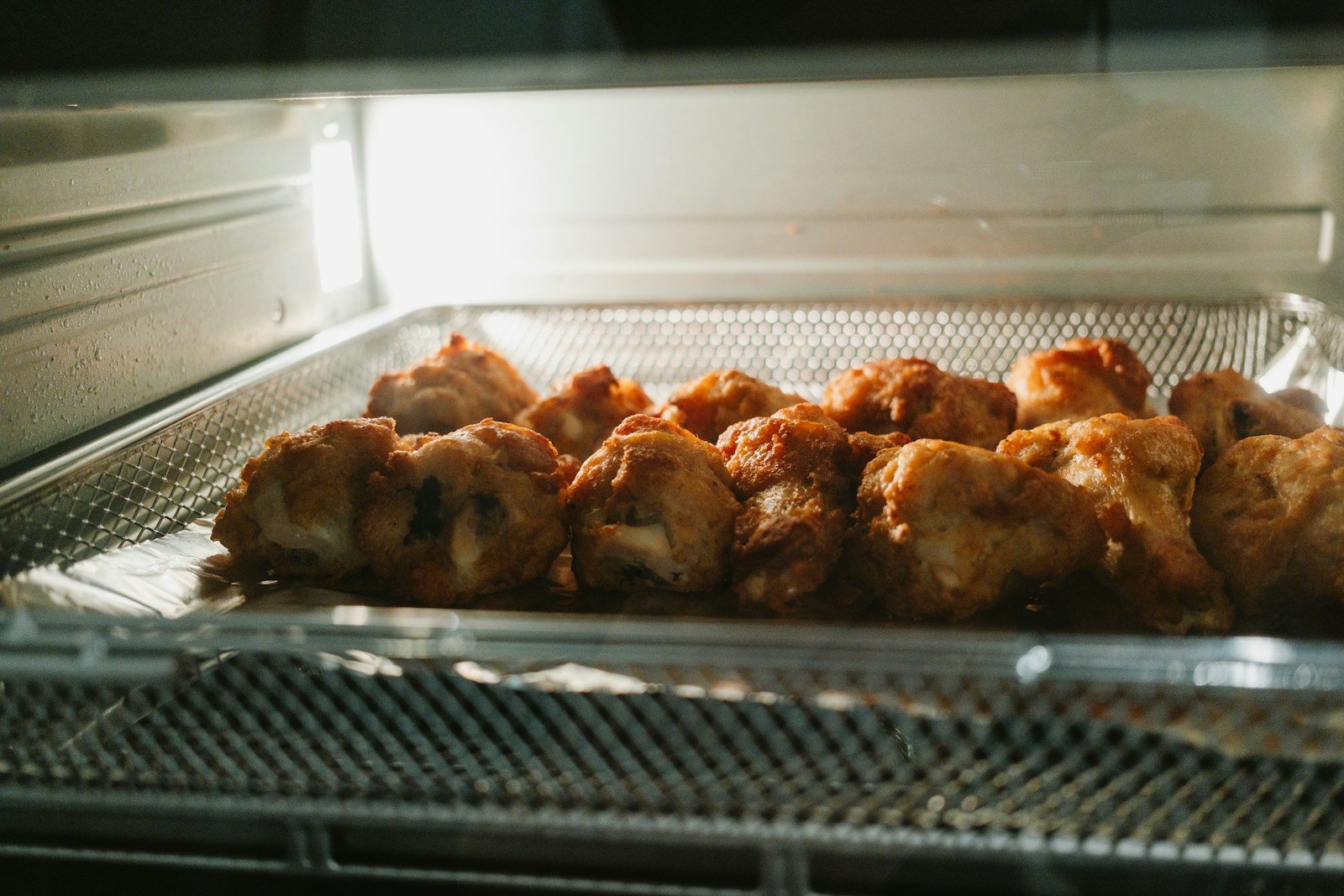 Piezas de pollo doradas en la canasta de una freidora de aire